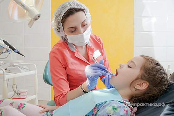 детский стоматолог лечит зубы ребенку